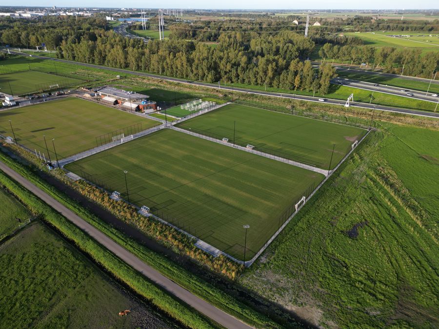 Luchtfoto van het sportpark van VSV met twee velden en het clubhuis in de avondzon