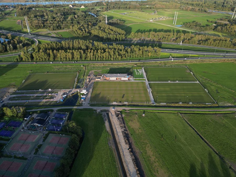 Wijd overzicht van het sportpark met tennis- en padelbanen op de voorgrond