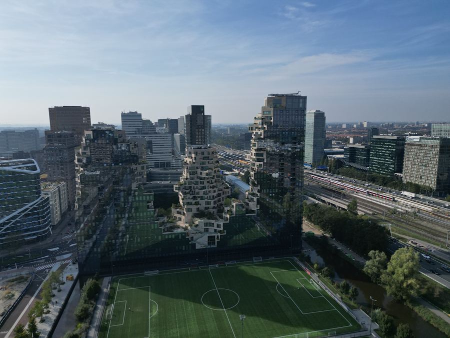 Een voetbalveld tussen de torens, met spoor en snelweg erachter