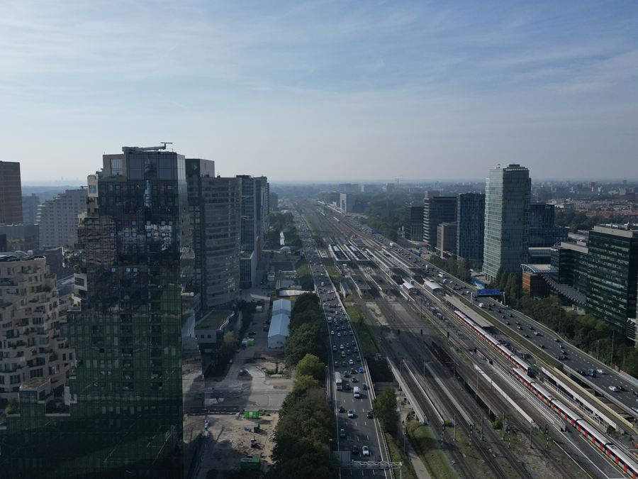 Zicht over spoor en snelweg tussen de kantoortorens