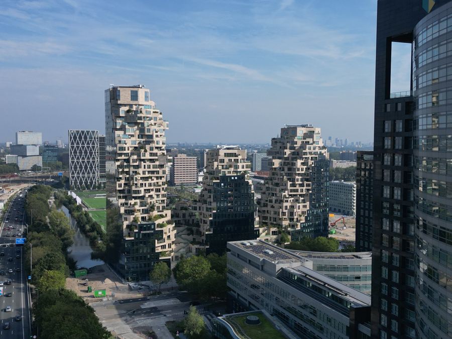 Woontorens met terrassen naast een donkere glazen toren